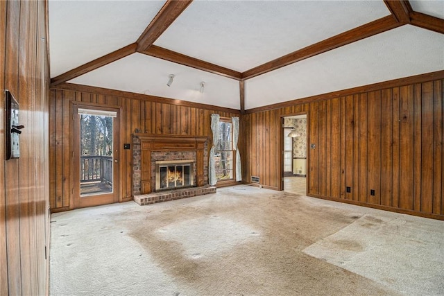 unfurnished living room with a wealth of natural light, wood walls, and a fireplace