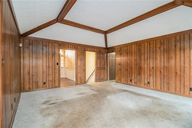 spare room featuring vaulted ceiling with beams, wood walls, and carpet floors