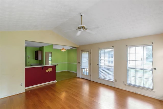 9550 Canvasback Ct, Jonesboro, GA 30238 - unfurnished living room with wood finished floors, baseboards, a ceiling fan, vaulted ceiling, and a textured ceiling