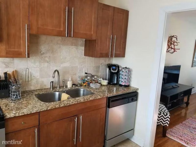 kitchen featuring backsplash, light hardwood / wood-style flooring, light stone countertops, sink, and stainless steel dishwasher