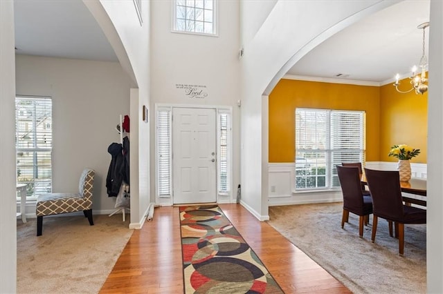 entryway with an inviting chandelier, light wood-type flooring, a healthy amount of sunlight, and crown molding