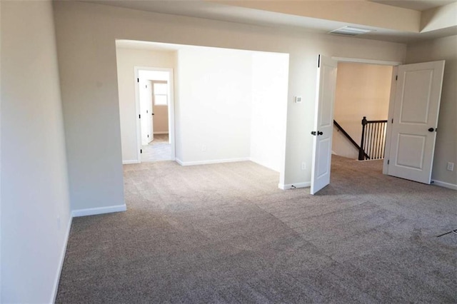 unfurnished room featuring carpet flooring, visible vents, and baseboards