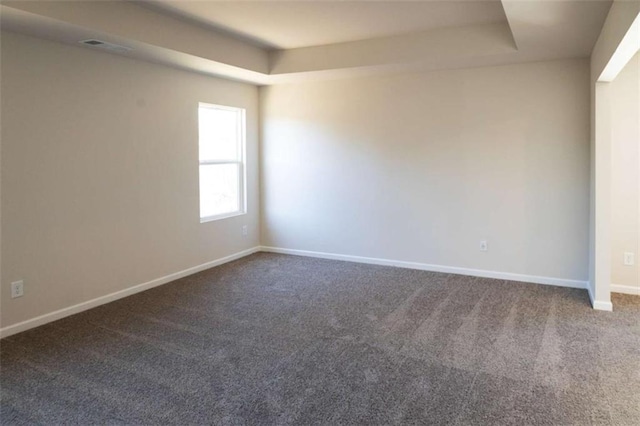 unfurnished room with carpet floors, a raised ceiling, visible vents, and baseboards