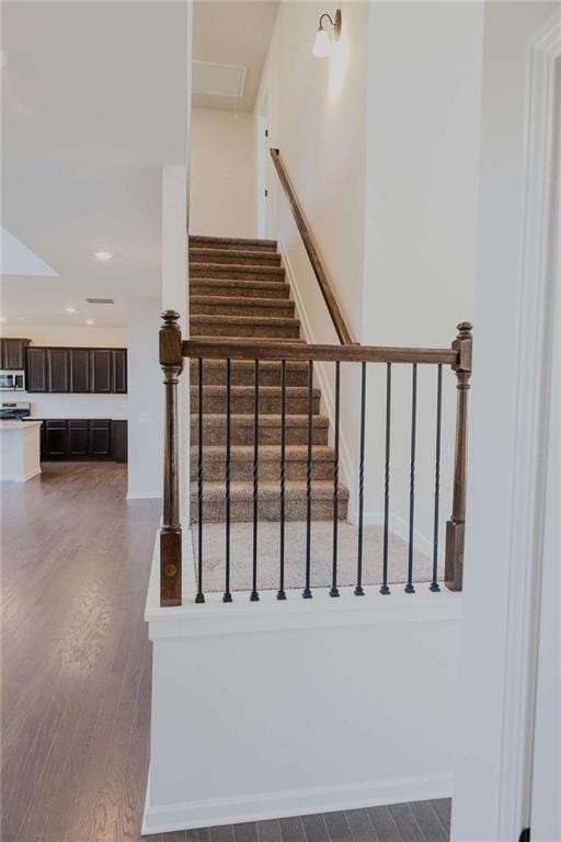 staircase with attic access, recessed lighting, and wood finished floors