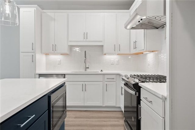 kitchen with stainless steel appliances, exhaust hood, light countertops, and white cabinetry