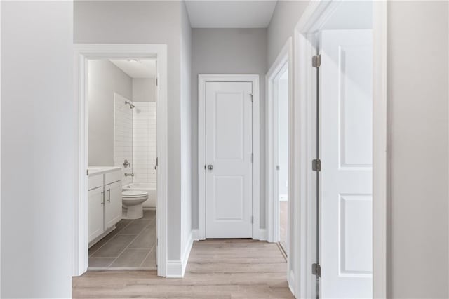 corridor with light wood finished floors and baseboards