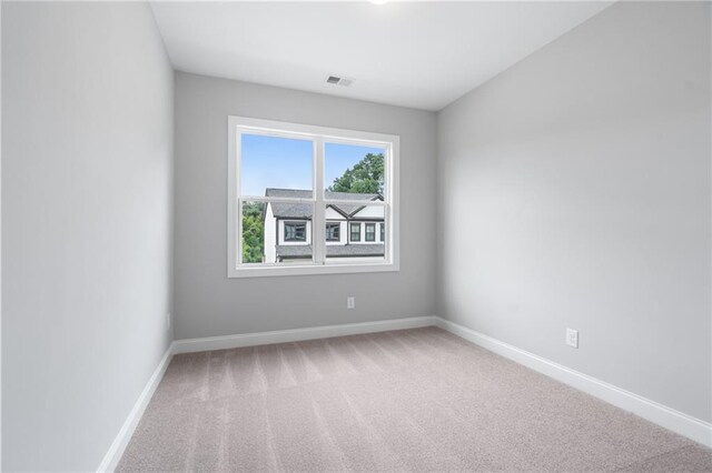 carpeted spare room featuring baseboards and visible vents