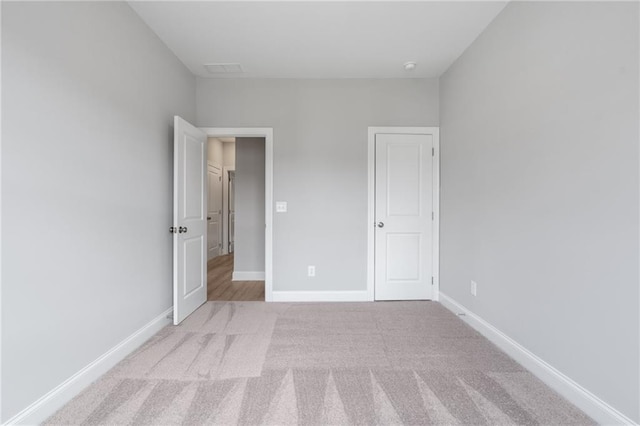 unfurnished bedroom featuring light colored carpet and baseboards