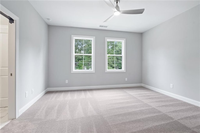 spare room with baseboards, ceiling fan, visible vents, and light colored carpet