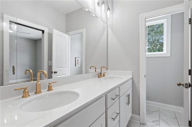 full bathroom with marble finish floor, a sink, baseboards, and double vanity