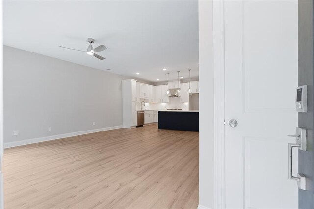 unfurnished living room featuring recessed lighting, light wood-style flooring, a ceiling fan, a sink, and baseboards