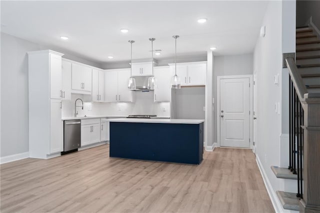 kitchen with a center island, light countertops, hanging light fixtures, stainless steel dishwasher, and white cabinets