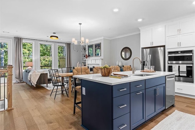 kitchen featuring blue cabinetry, sink, appliances with stainless steel finishes, a kitchen island with sink, and white cabinets