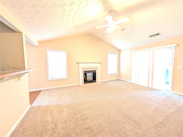 unfurnished living room featuring a textured ceiling, carpet, ceiling fan, and vaulted ceiling