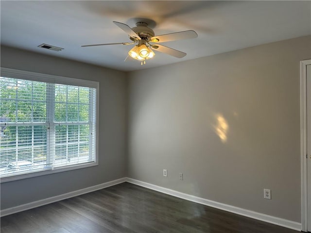 empty room with visible vents, a ceiling fan, dark wood-style flooring, and baseboards