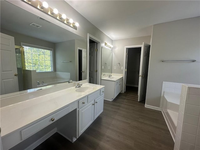 full bath featuring a sink, a garden tub, wood finished floors, and visible vents