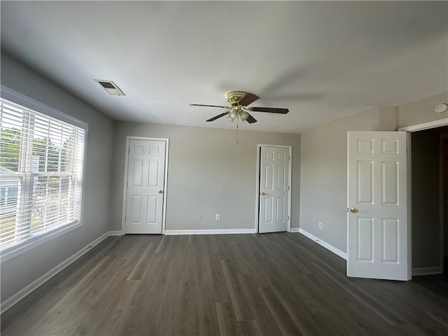 unfurnished bedroom with a ceiling fan, baseboards, visible vents, and dark wood-style floors