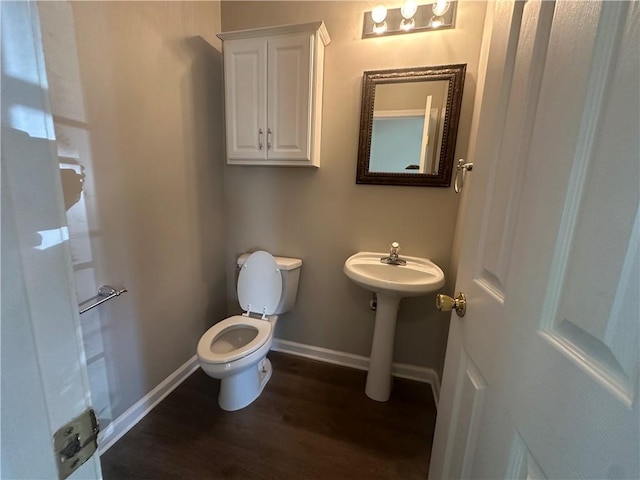 half bathroom with baseboards, wood finished floors, and toilet