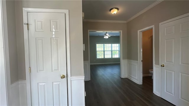 hallway featuring ornamental molding, dark wood-style flooring, and wainscoting