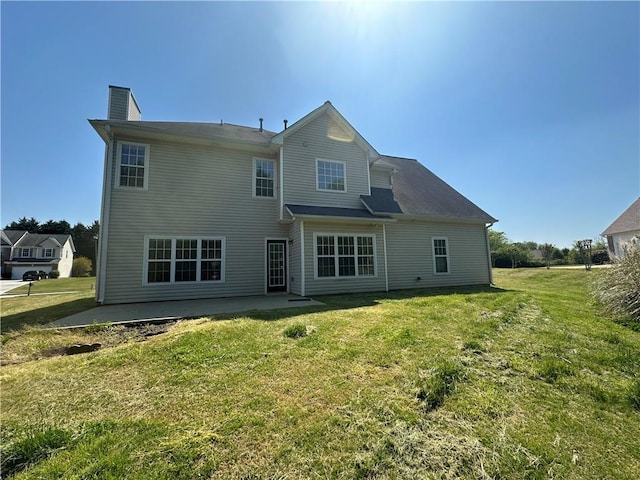 rear view of house with a lawn, a patio area, and a chimney