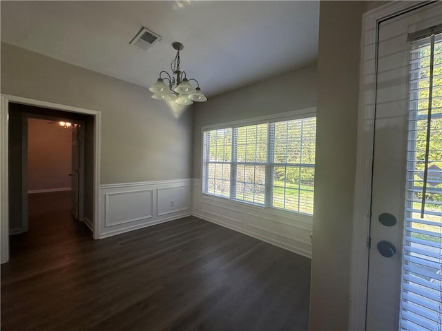 unfurnished dining area with a healthy amount of sunlight, dark wood finished floors, a chandelier, and visible vents