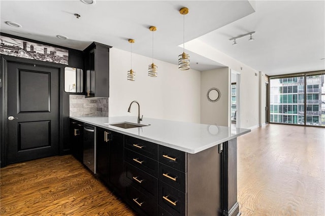 kitchen with backsplash, dark wood-type flooring, sink, hanging light fixtures, and kitchen peninsula