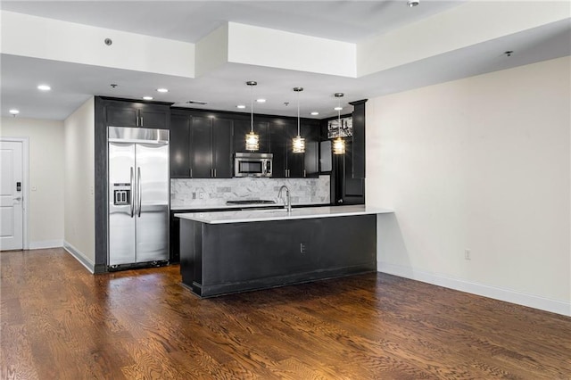 kitchen with stainless steel appliances, dark hardwood / wood-style floors, kitchen peninsula, pendant lighting, and decorative backsplash