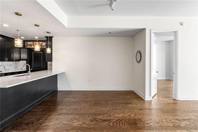 kitchen with sink, tasteful backsplash, dark hardwood / wood-style flooring, kitchen peninsula, and pendant lighting