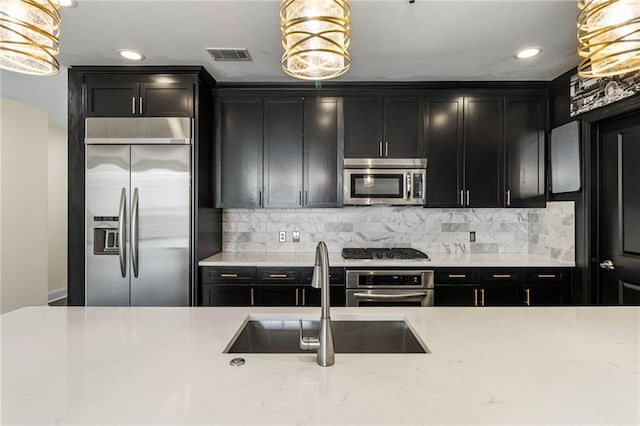 kitchen featuring backsplash, sink, decorative light fixtures, and appliances with stainless steel finishes