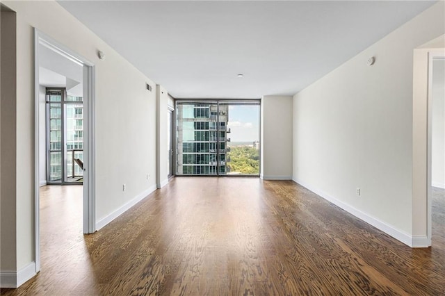 unfurnished room featuring a wealth of natural light, dark hardwood / wood-style flooring, and expansive windows