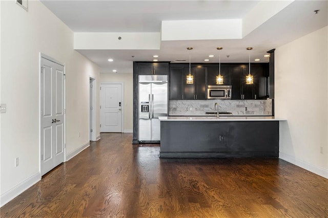 kitchen featuring tasteful backsplash, stainless steel appliances, dark wood-type flooring, sink, and decorative light fixtures