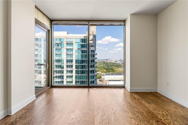 spare room with hardwood / wood-style flooring and a wall of windows