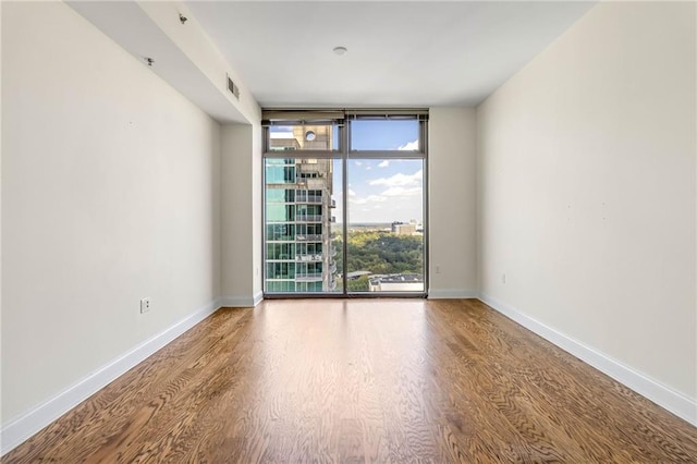 unfurnished room with wood-type flooring and floor to ceiling windows