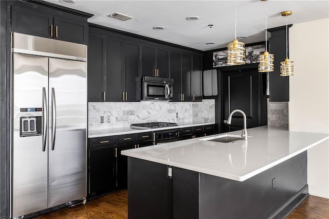 kitchen featuring appliances with stainless steel finishes, tasteful backsplash, sink, pendant lighting, and dark hardwood / wood-style floors