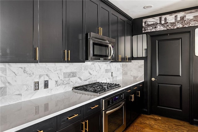 kitchen featuring backsplash, dark hardwood / wood-style flooring, light stone countertops, and stainless steel appliances