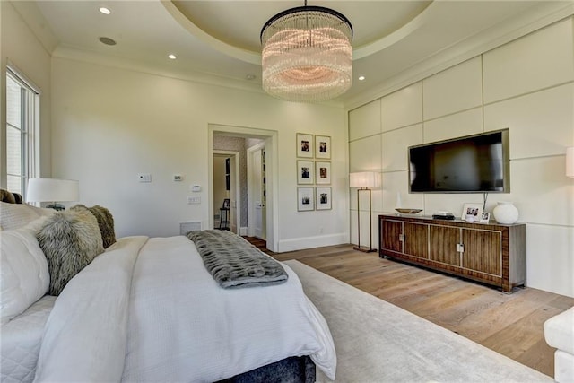 bedroom featuring visible vents, an inviting chandelier, wood finished floors, baseboards, and a tray ceiling