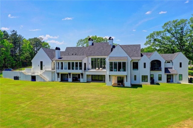 rear view of house with a lawn, a chimney, and cooling unit