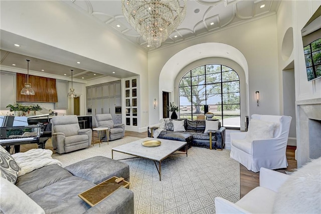 living area featuring wood finished floors, a high ceiling, a chandelier, ornamental molding, and a premium fireplace
