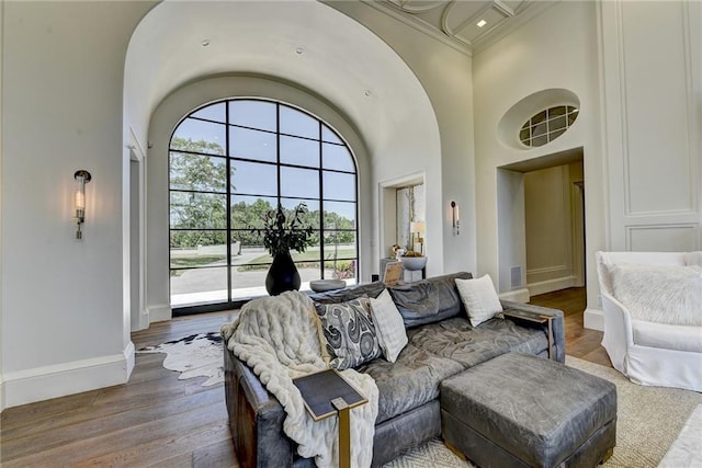 living area featuring crown molding, baseboards, a high ceiling, and wood finished floors