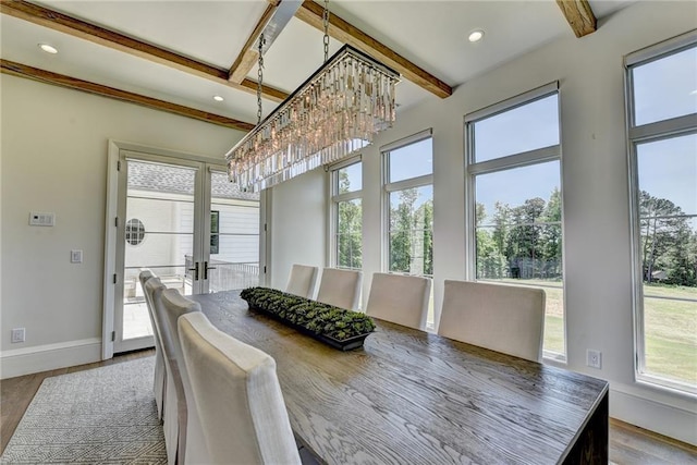 dining space featuring a healthy amount of sunlight, wood finished floors, beam ceiling, and a notable chandelier