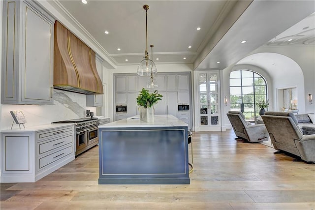 kitchen with light wood-style floors, open floor plan, custom exhaust hood, and range with two ovens