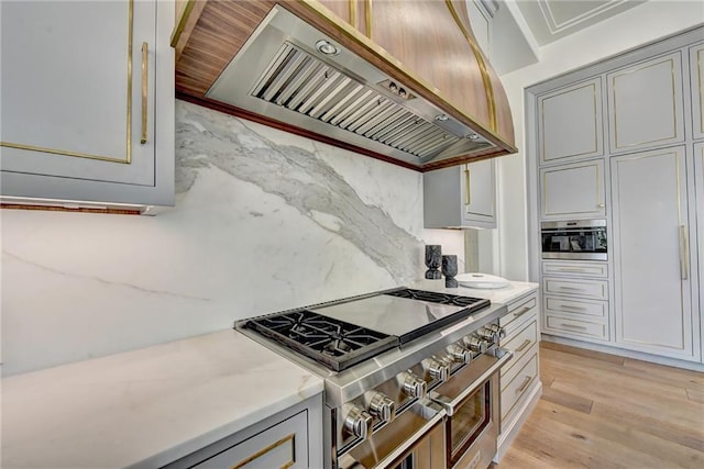 kitchen with gray cabinetry, extractor fan, double oven range, and light wood finished floors