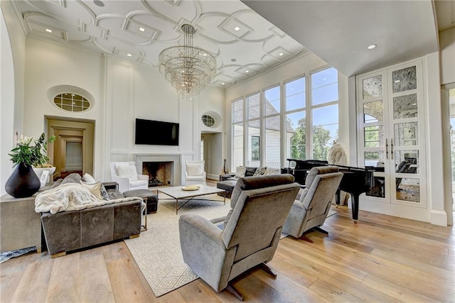 living room with ornamental molding, a notable chandelier, light wood-style flooring, and a towering ceiling