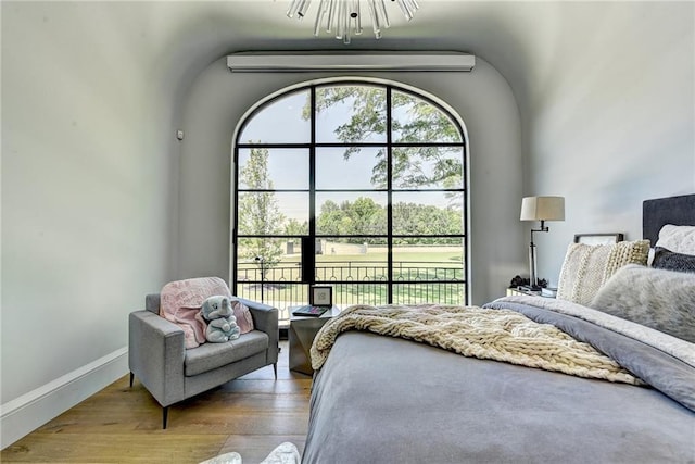 bedroom featuring baseboards, wood finished floors, and a chandelier