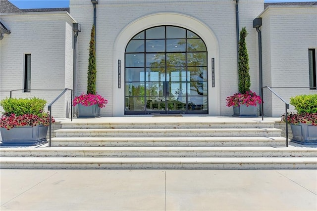 entrance to property featuring covered porch and brick siding