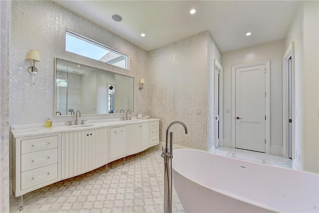 bathroom with double vanity, tile patterned floors, a sink, and a soaking tub