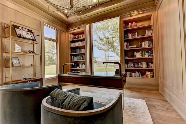 home office featuring wood finished floors, a notable chandelier, and built in shelves
