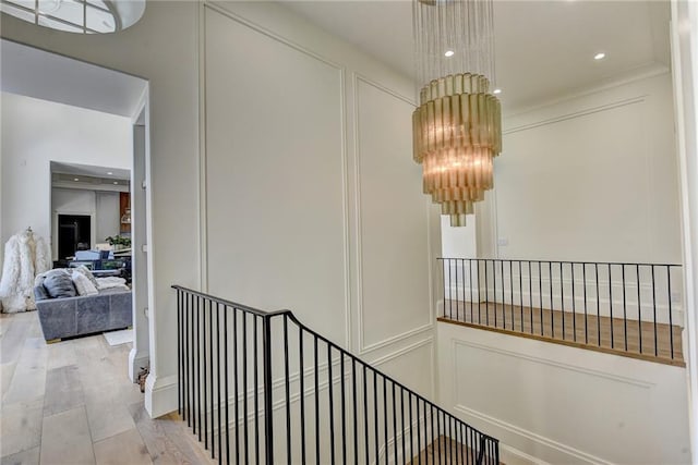 corridor featuring an inviting chandelier, a decorative wall, and an upstairs landing