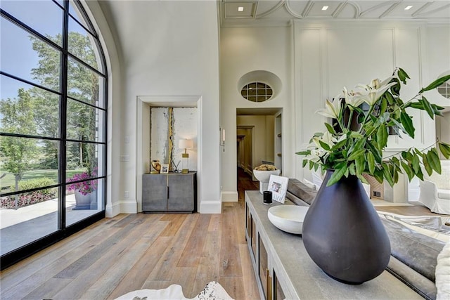 interior space featuring light wood-type flooring, recessed lighting, plenty of natural light, and a high ceiling
