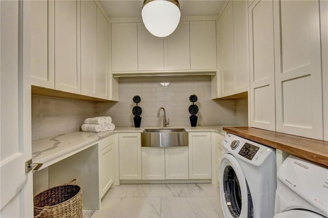 washroom with a sink, marble finish floor, cabinet space, and washer and clothes dryer